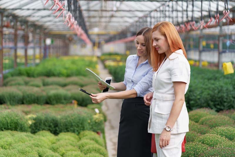 Two business women having a conversation while visiting greenhouse